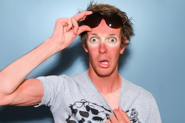 Man raises his sunglasses in shock at his sunburn